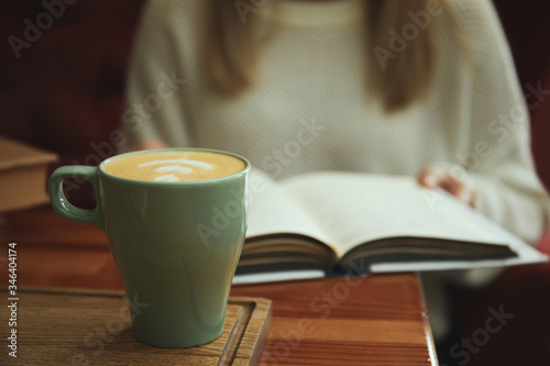 Woman with coffee reading book indoors  focus on cup
