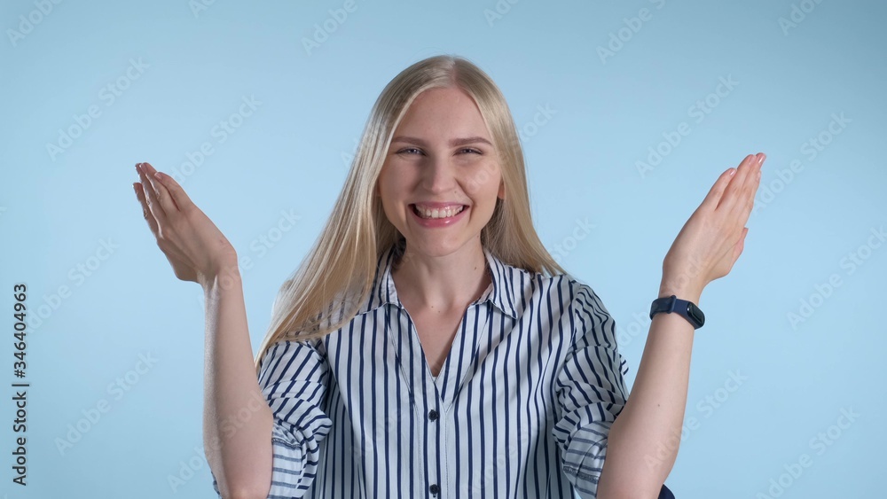 Beautiful woman covering her face with hands, then opening it and smiling. Blue background. Beautiful woman covering her face with hands, then opening it and smiling. Blue background.