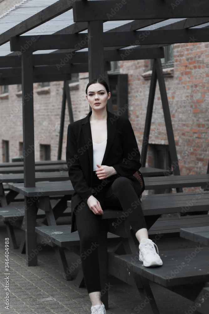 young caucasian woman in  black suit sit alone outdoor