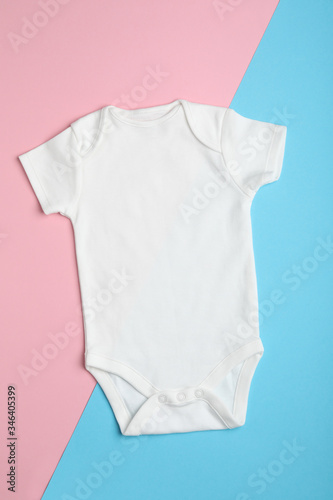 Child's bodysuit on light blue and pink background, top view