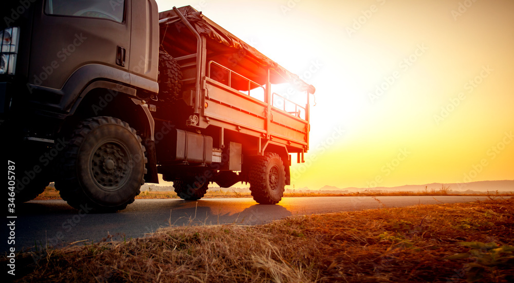 military truck running on asphalt highway against beautiful sunset sky military truck running on asphalt highway against beautiful sunset sky