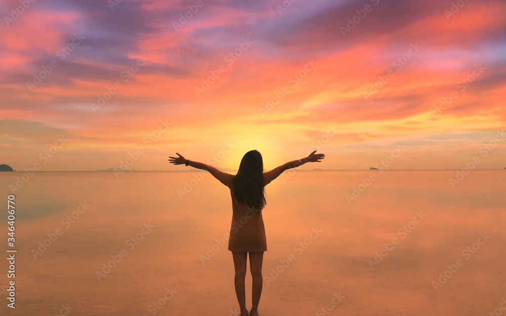 Happy Freedom Woman raised hands on calm sea water surface looking at sunset Girl lifting arm up celebrating scenic landscape enjoying vacation travel adventure nature Camera boom up