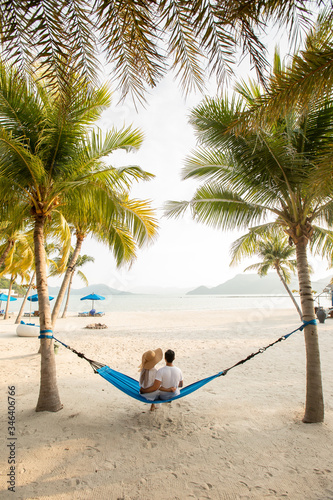 a couple loving hug each other while seating on a hammock at the beach