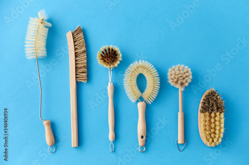 natural cleaning stuff  sustainability and eco living concept - different brushes with wooden handles on blue background