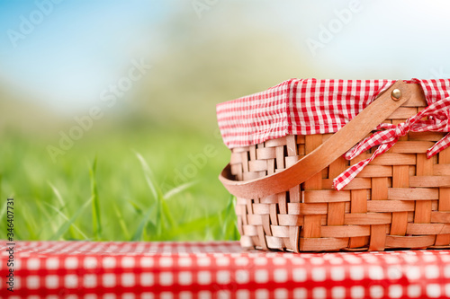 Picnic and summer mood. Picnic basket, on a table with a red tablecloth. Against the background of the landscape. Concept of weekend and summer moods.