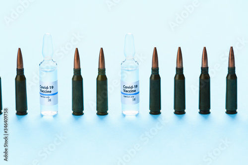 Covid 19 coronavirus bullets in a row with medical ampoules. Dangerous vaccine photo