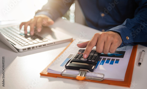 Male businessman working on desk office with using a calculator to calculate the numbers  finance accounting concept.