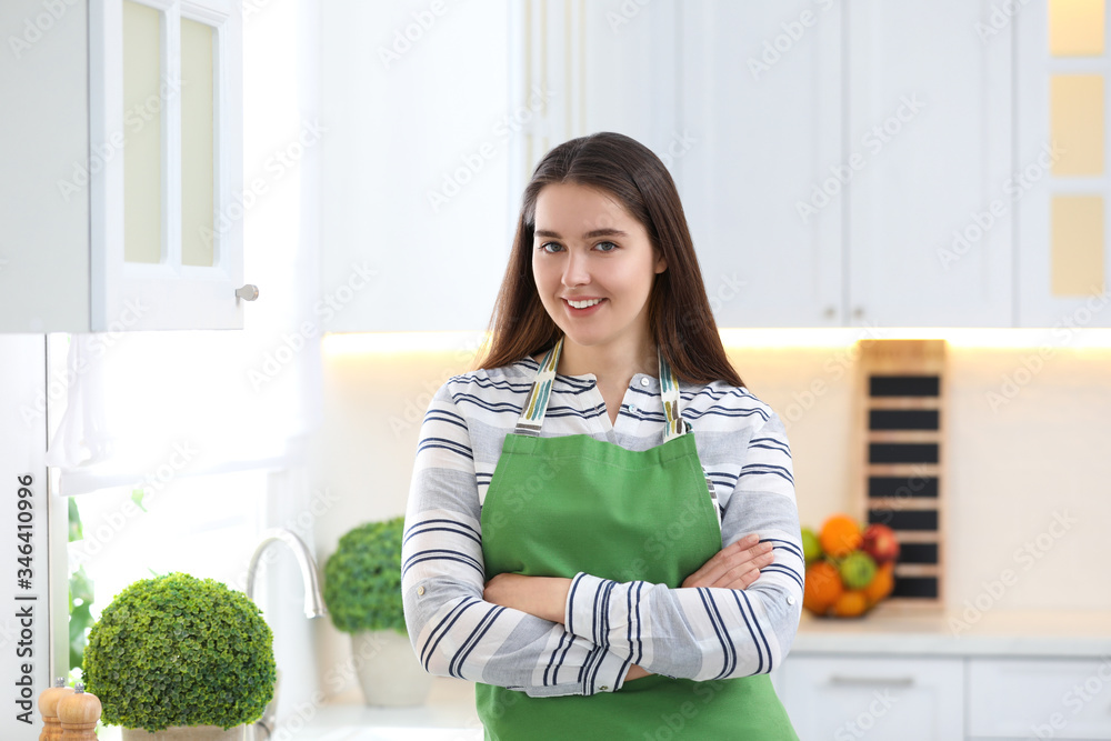 Portrait of young woman with apron in kitchen Portrait of young woman with apron in kitchen