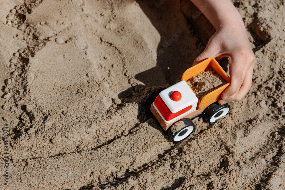 children's hand plays with a truck in the sand