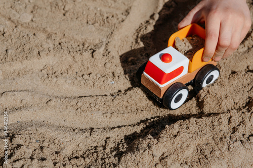 children's hand plays with a truck in the sand