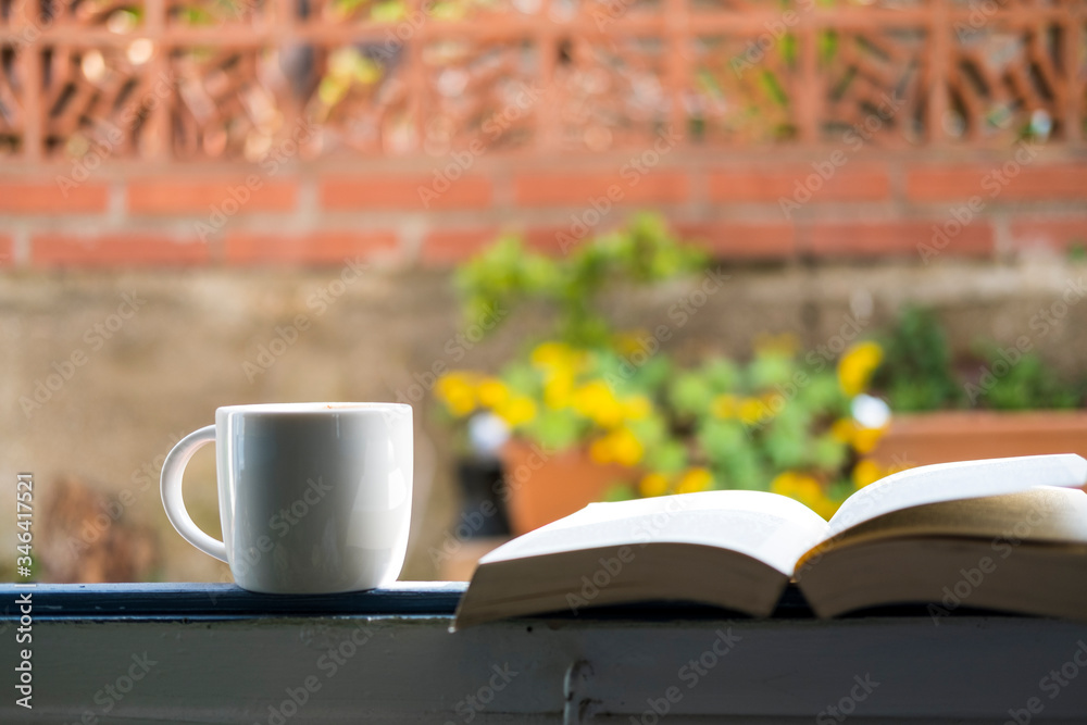 white cup with cappuccino coffee in a window overlooking a flowered terrace white cup with cappuccino coffee in a window overlooking a flowered terrace