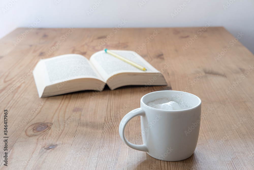 cup with coffee and a open book on a rustic wooden table cup with coffee and a open book on a rustic wooden table