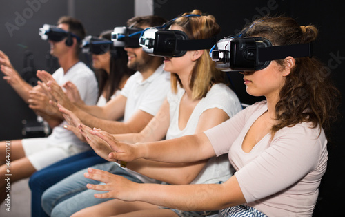 Young girl is enjoying exciting movie with friends in VR glasses © JackF