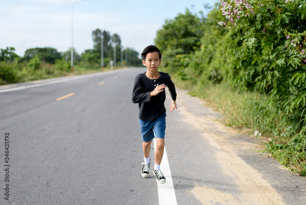 Young Asian boy running on a road