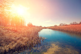 Magical sunset in the countryside. Rural landscape in spring. Narrow river in the evening