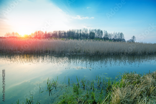 Magical sunset in the countryside. Rural landscape in spring, wilderness. Narrow river in the evening