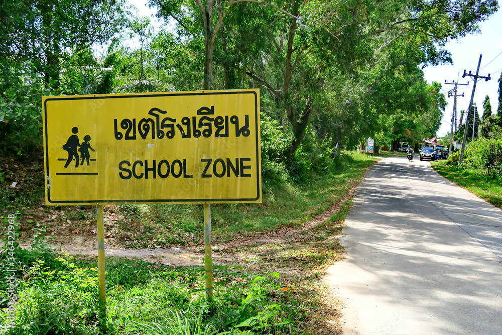Panneau bilingue anglais-thai au bord de la route: School Zone. Thailande.