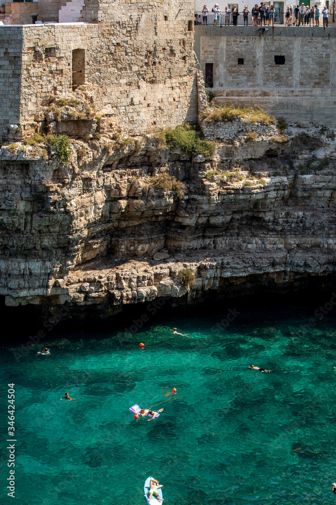  People relax and swimming on lovely beach Lama Monachile in Polignano a Mare, Adriatic Sea, Apulia, Bari province, Italy,