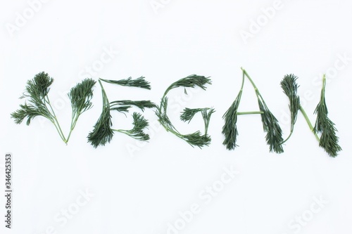 Obraz na płótnie Vegan written from dill and herbs. Concepts for design. The word vegan on a white background, top view. Vegan food concept w salonie