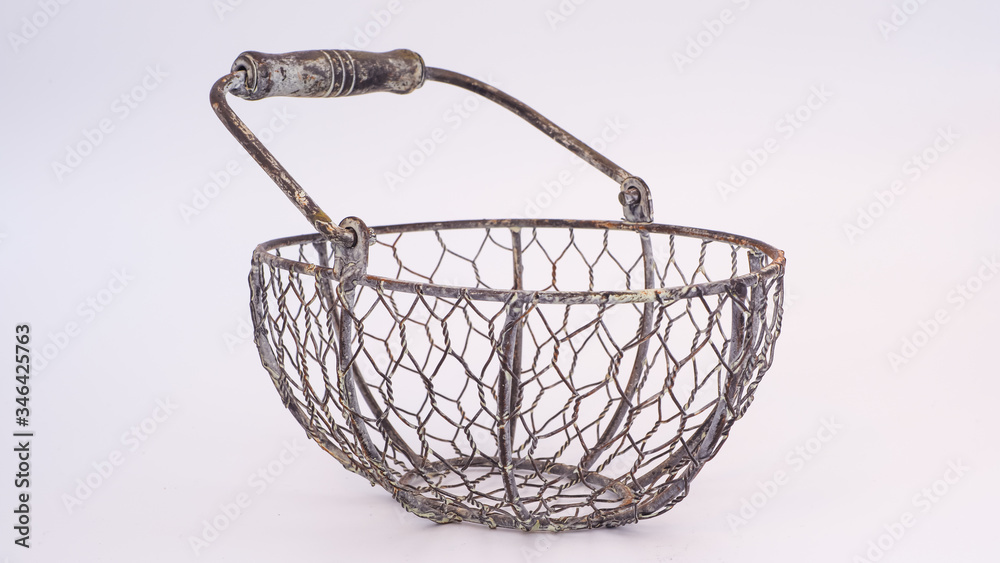 Decorative metal frame basket with chicken wire mesh and a wooden handle on a plain white background. Rust and fatigued paint finish. Rustic decorative item Decorative metal frame basket with chicken wire mesh and a wooden handle on a plain white background. Rust and fatigued paint finish. Rustic decorative item