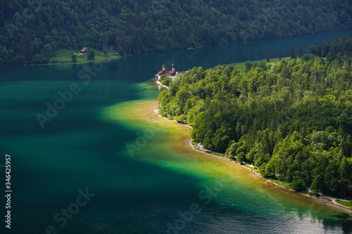 View from above towards the green waters of Konigsee lake and Saint Bartholomew church in Berchtesgaden National Park in Germany 