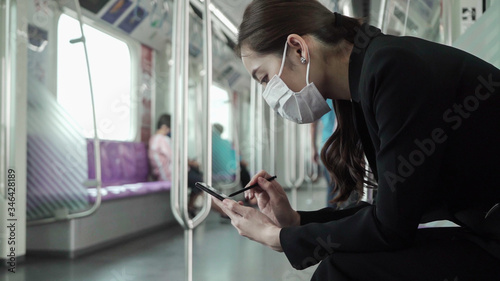Businesswoman are using their smartphones while traveling on the train to work while the coronavirus is spreading. 