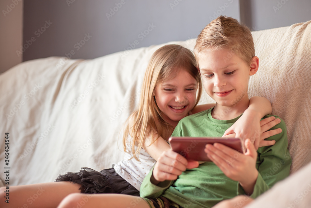 kids play telephen, watch videos on gadgets lying on the couch