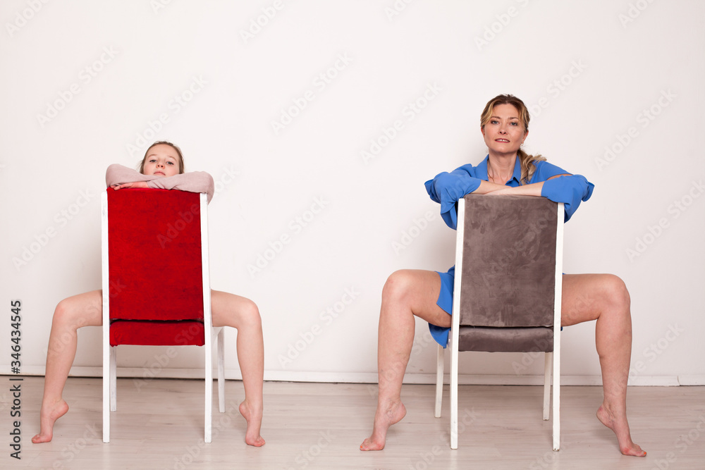 Fototapeta premium Mom and daughter sit on chairs in white room