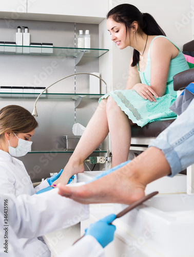 Pair of women clients getting pedicure in modern nail salon