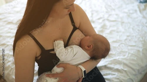 Mother breastfeeds little baby girl at home