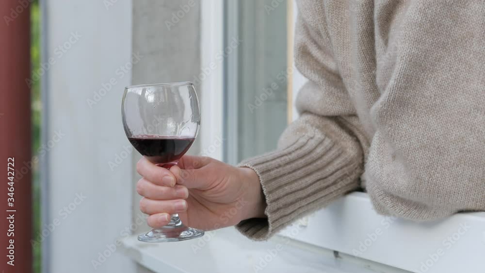 Closeup of a female hand with a glass in a window