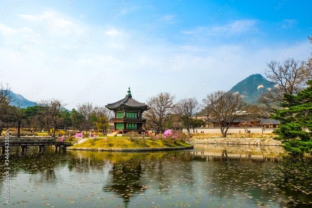 Hyangwonjeong Pavilion on an artificial island of Hyangwonji lake under bright blue sky with Mount Bugak as backdrop on springtime. It's location is in Gyeongbokgung Palace.