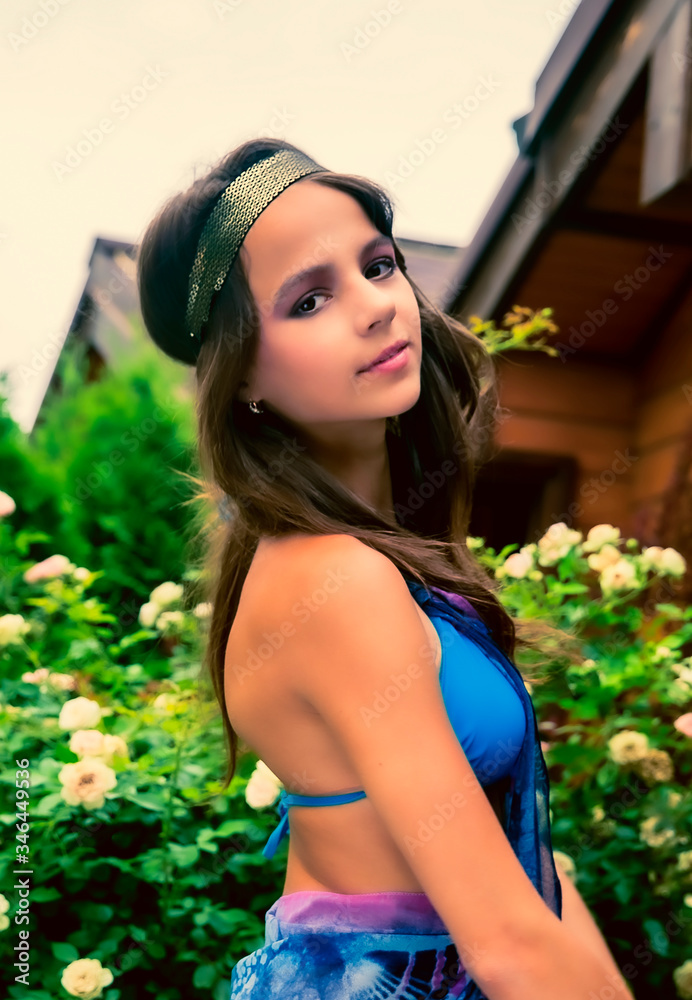 Beautiful young woman posing against a backdrop of greenery and a bungalow with a blue tissue. Elegant girl with scarf and bijouterie enjoying at beach. Freedom and carefree concept, Bali. tanning Beautiful young woman posing against a backdrop of greenery and a bungalow with a blue tissue. Elegant girl with scarf and bijouterie enjoying at beach. Freedom and carefree concept, Bali. tanning