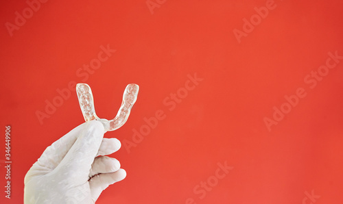 Invisible bracelets on a red background held in one hand by a latex glove