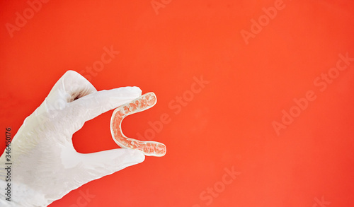 Invisible bracelets on a red background held in one hand by a latex glove