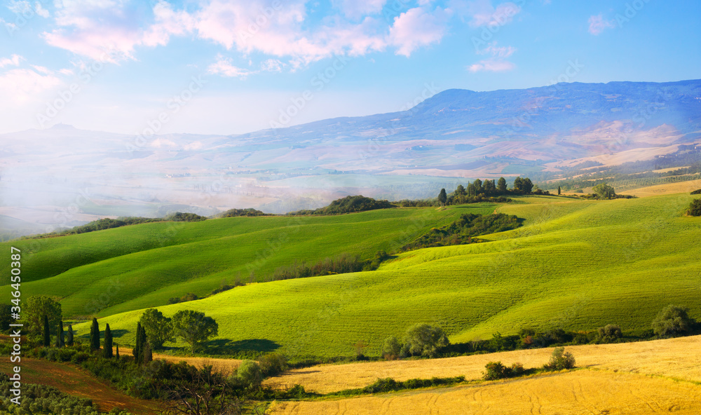 panoramic view of Italian Tuscany landscape of wheat field, green and yellow farmland hills