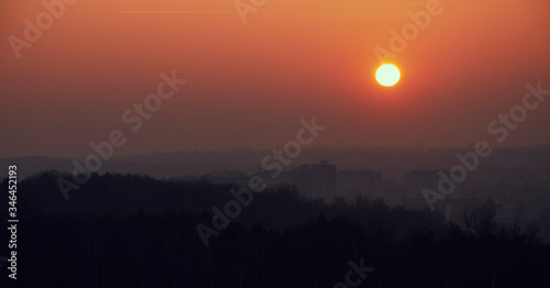 Orange sunset seen from the Krak's Mound in the background smog over the city