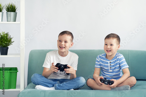 small children play video games on a blue sofa.