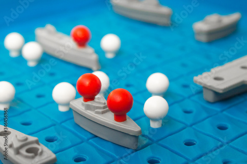 Battleship, board game. Sea battle. Toy ships on a plastic board. Perfect hit. Victory or defeat. Blue background, blur.