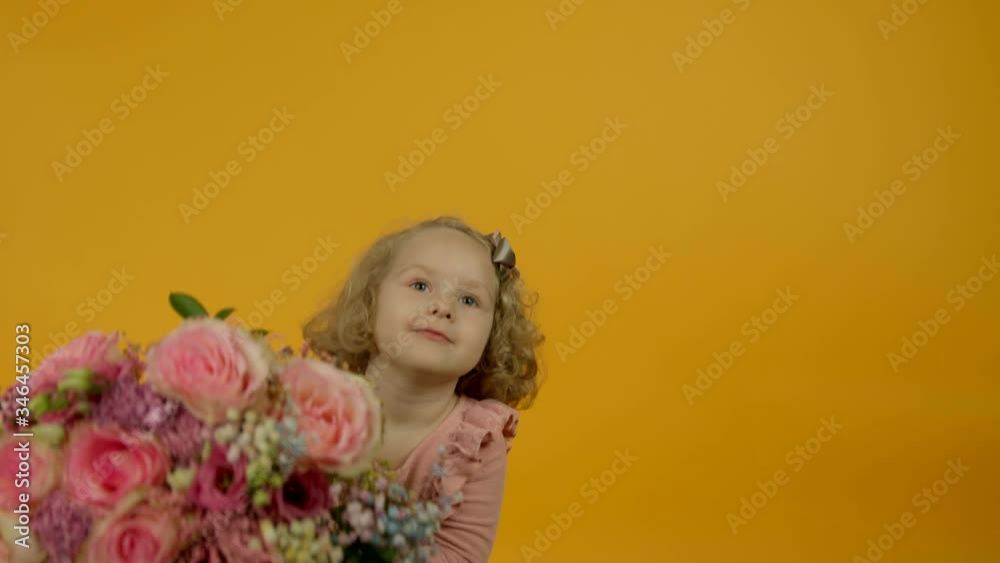 Curly kid jumping and looking at flowers with interest Curly kid jumping and looking at flowers with interest