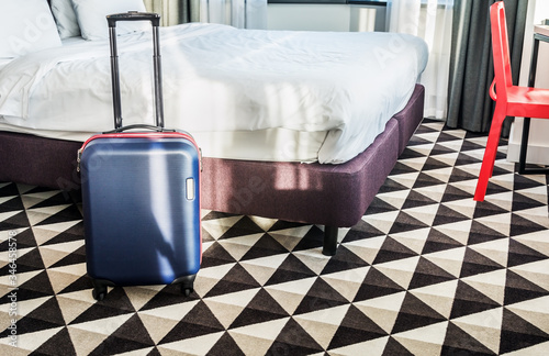 Konstfotografi suitcase stands by the bed in the hotel room