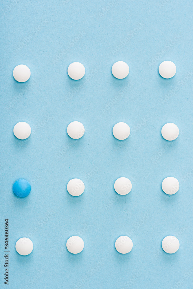 Flat lay with unique pill among white on blue background Flat lay with unique pill among white on blue background