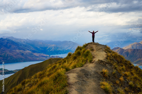 Woman standing on top of a mountain, view of lakes. Roy's Peak, Wanaka, New Zeland