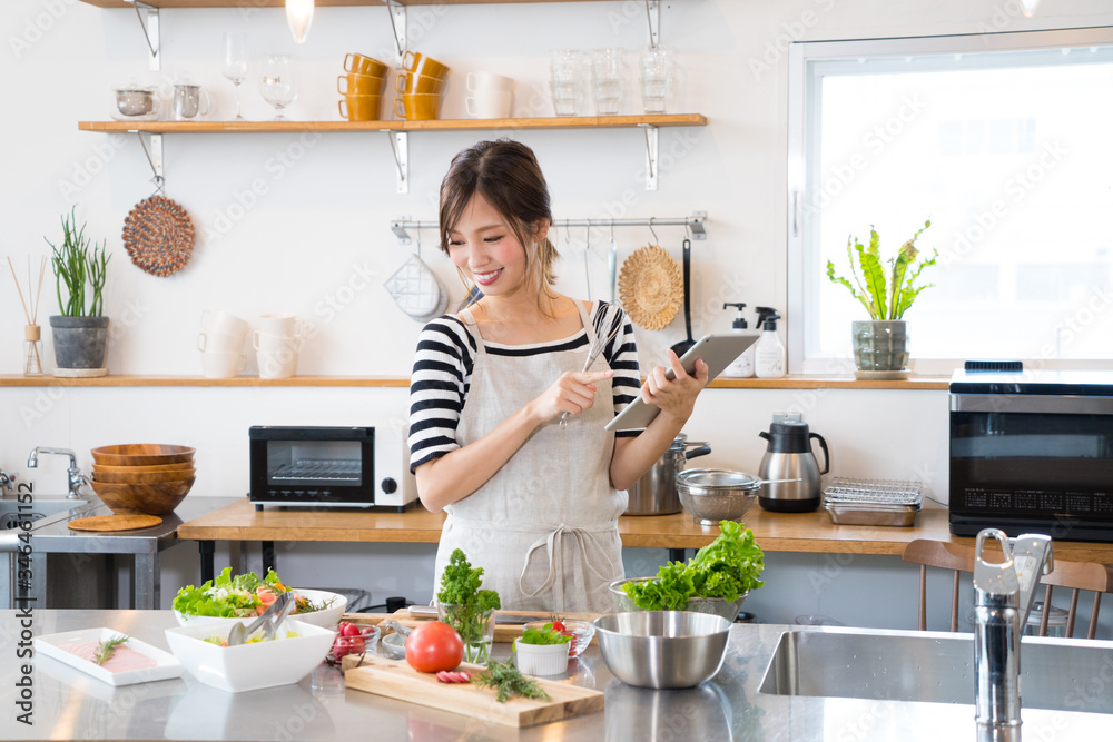 タブレットを見ながら料理を作る若い女性 タブレットを見ながら料理を作る若い女性