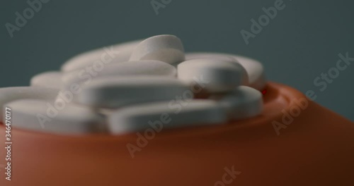 Macro close up of cluster of white vitamin supplements balancing and rotating on orange surface photo