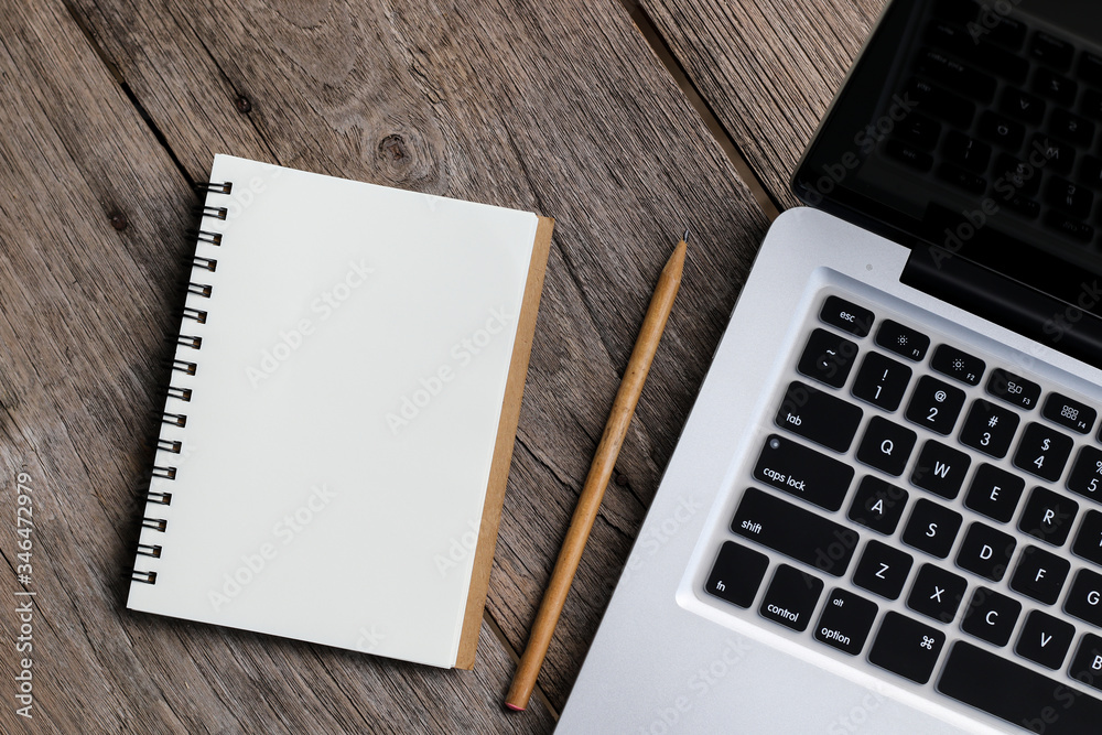 Blank notebook with laptop beside on wooden table Blank notebook with laptop beside on wooden table
