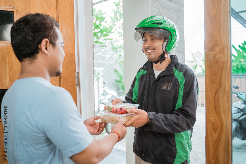 Delivery man delivering food to a man at home - online food shopping service concept Delivery man delivering food to a man at home - online food shopping service concept
