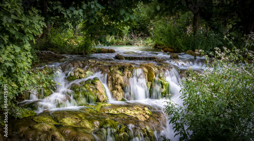 tranquil little long exposure waterfall in a green foliage woodland at spring time