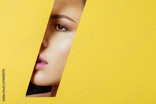 Woman looking across quadrangular hole in yellow paper