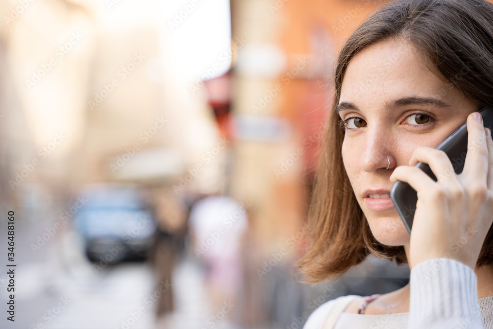 Woman with half a mane and a pierced nose talking with a phone with worried expression Woman with half a mane and a pierced nose talking with a phone with worried expression